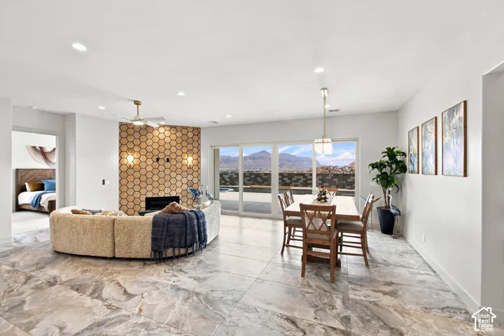 Spacious living area featuring large format stone-look tile flooring, a fireplace with a hexagonal tile surround, and a ceiling fan