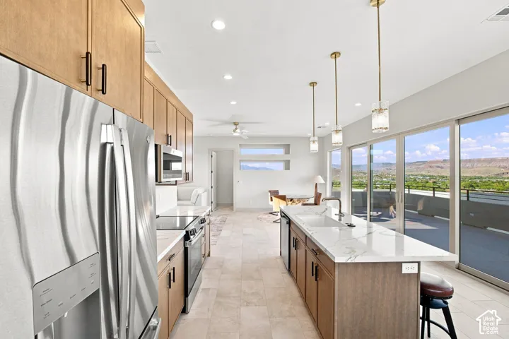 Gourmet kitchen with stainless steel appliances, wood-finish cabinetry, a large center island with a sink, and sliding glass doors to the exterior
