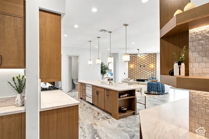 Open concept design featuring a central kitchen island with seating, a gas cooktop, pendant lighting, and stone flooring