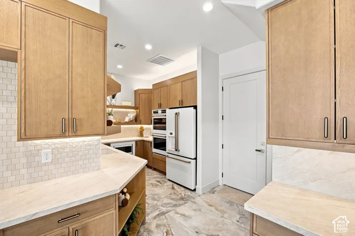 Contemporary kitchen with wood-finish cabinetry, light-toned stone countertops, and a subway tile backsplash