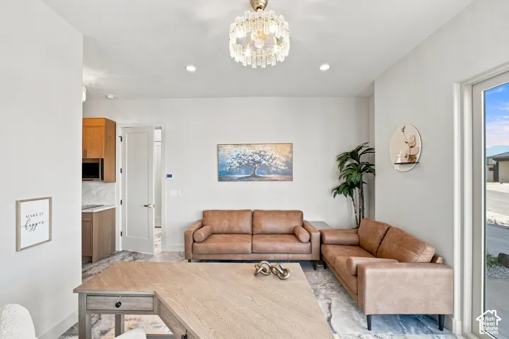 Recessed lighting, contemporary chandelier, wood-finish flooring, white walls, and a glass-paneled exterior door