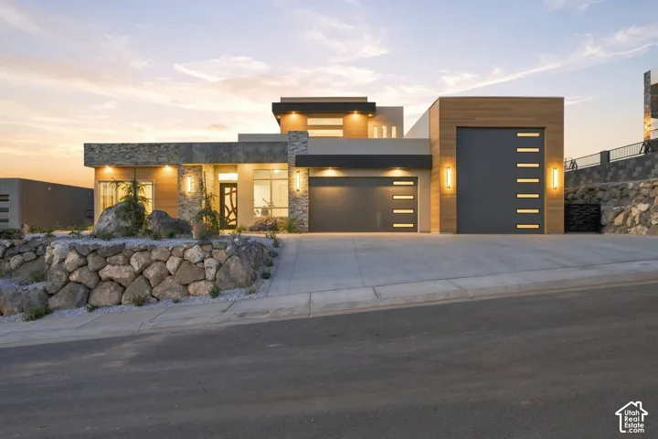 Contemporary exterior featuring stone accents, wood-paneled sections, and multiple garage doors