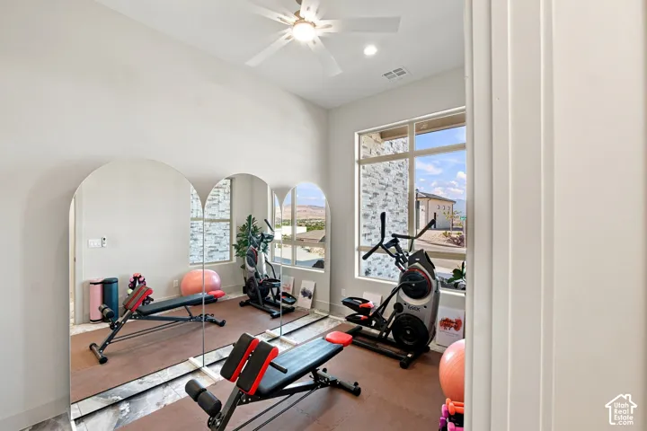 High ceilings with a ceiling fan, large windows, and full-height wall mirrors