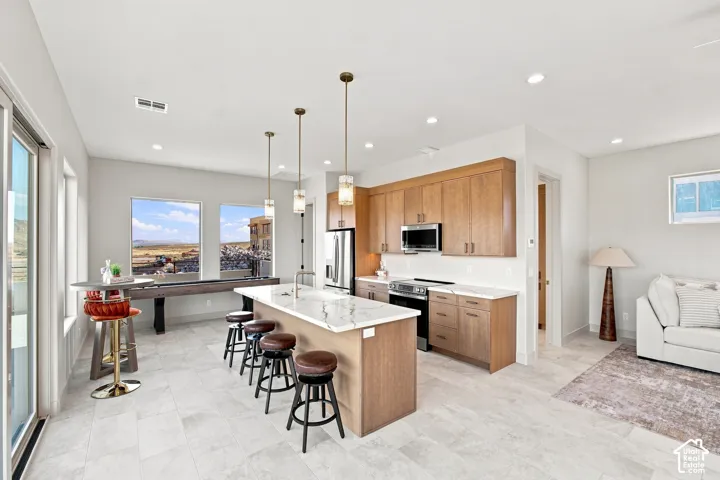 Modern kitchen with wood-finish cabinetry, stainless steel appliances, and a central island with a waterfall countertop