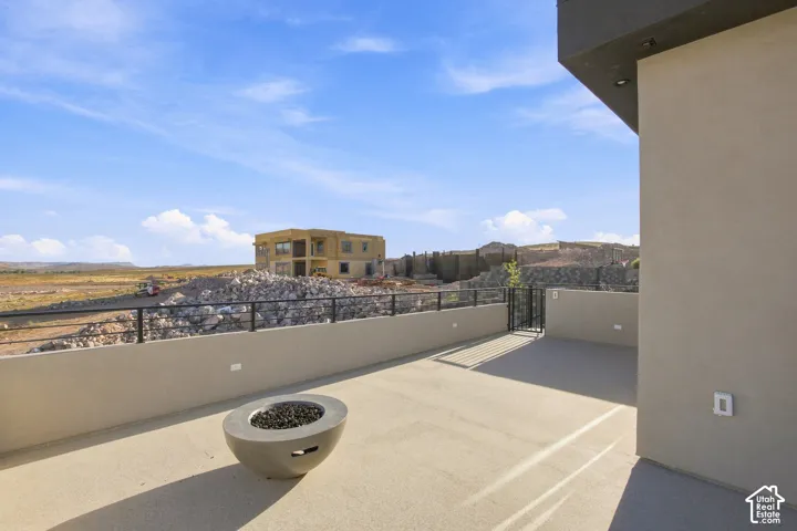 Expansive outdoor deck featuring a concrete fire pit, black metal railings, and a secure gate