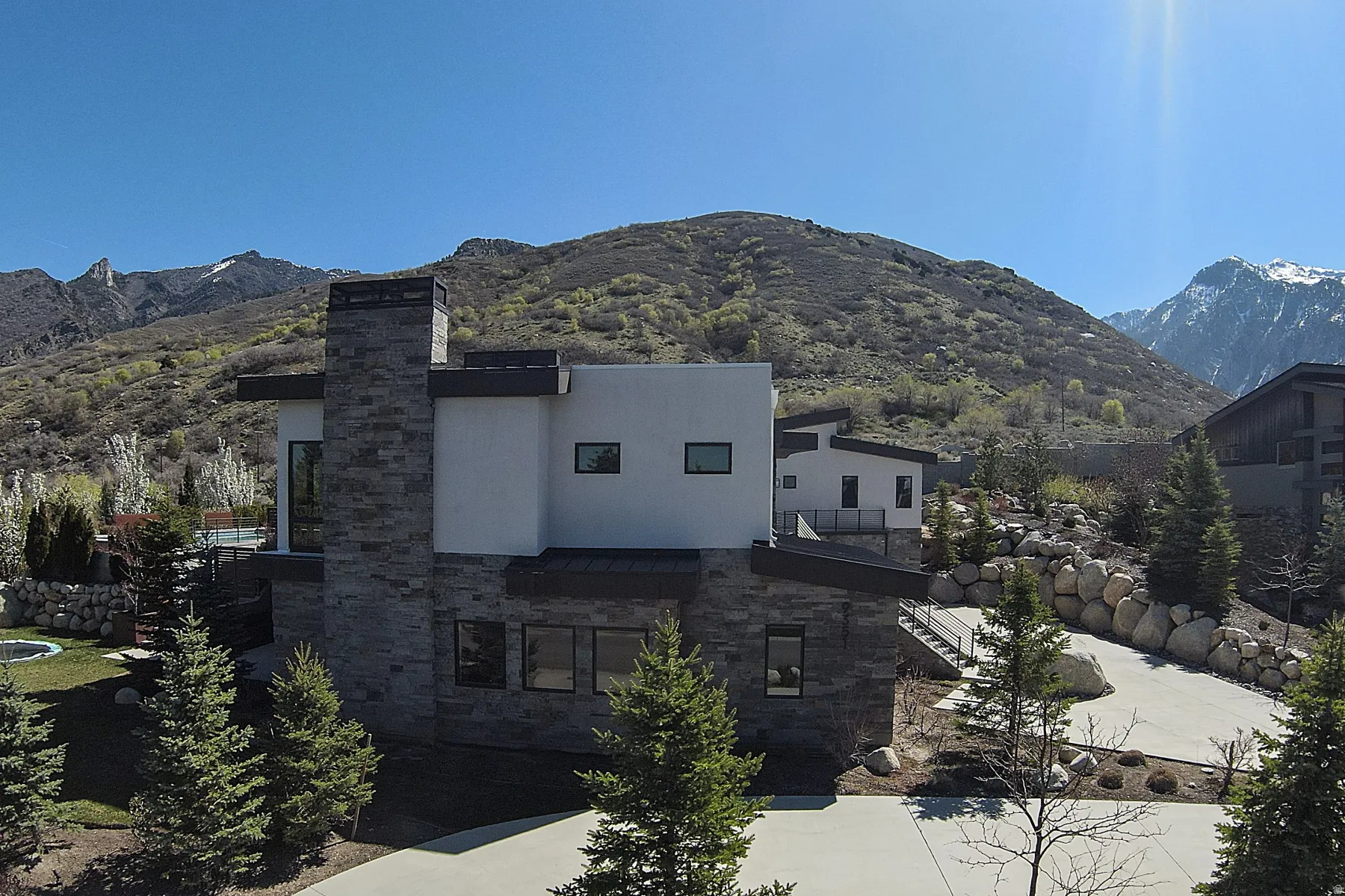 Modern architectural residence featuring a stone-clad chimney and a contrasting white facade