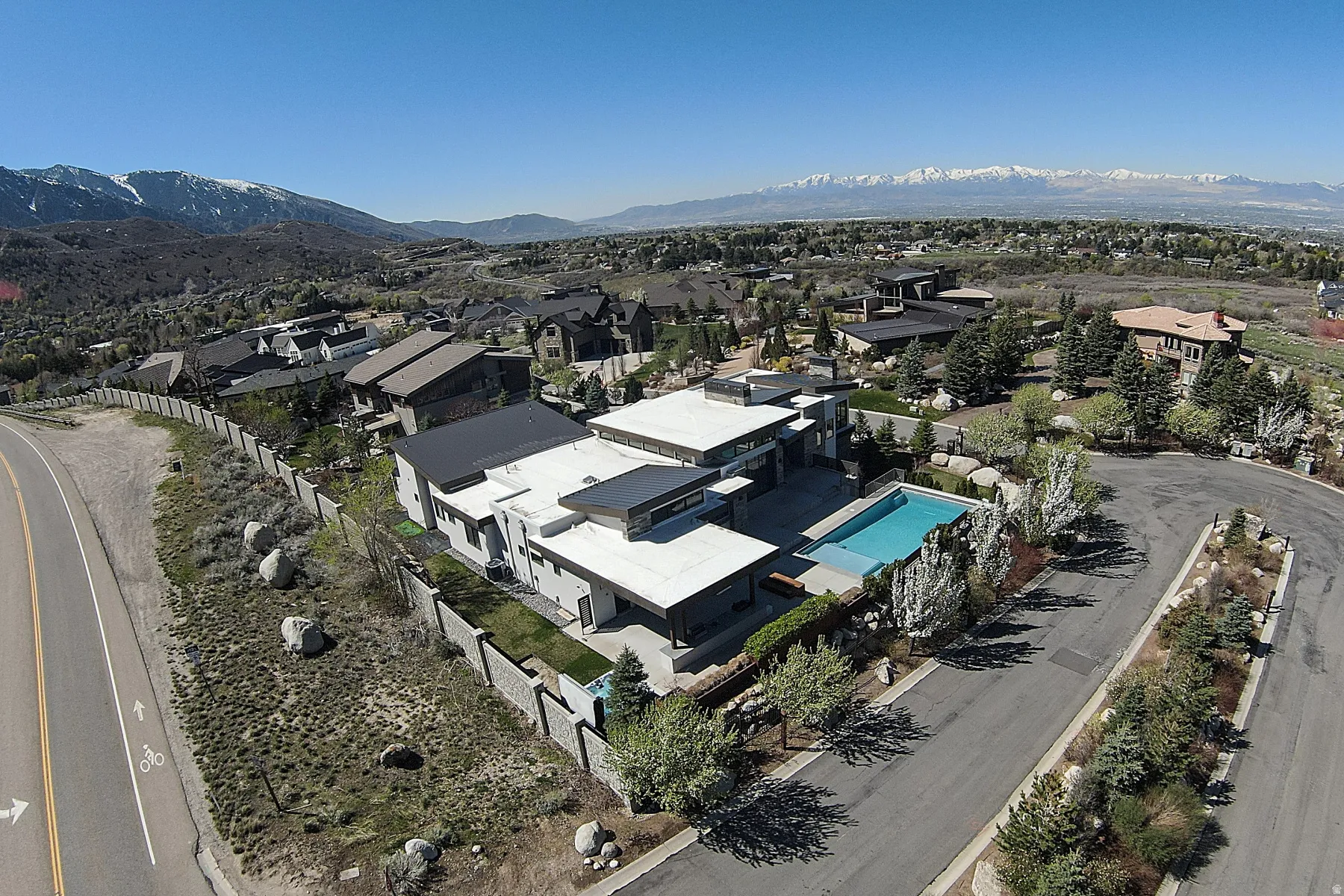 Modern architectural residence featuring a flat roofline, an exterior pool, a substantial privacy wall, and mature landscaping