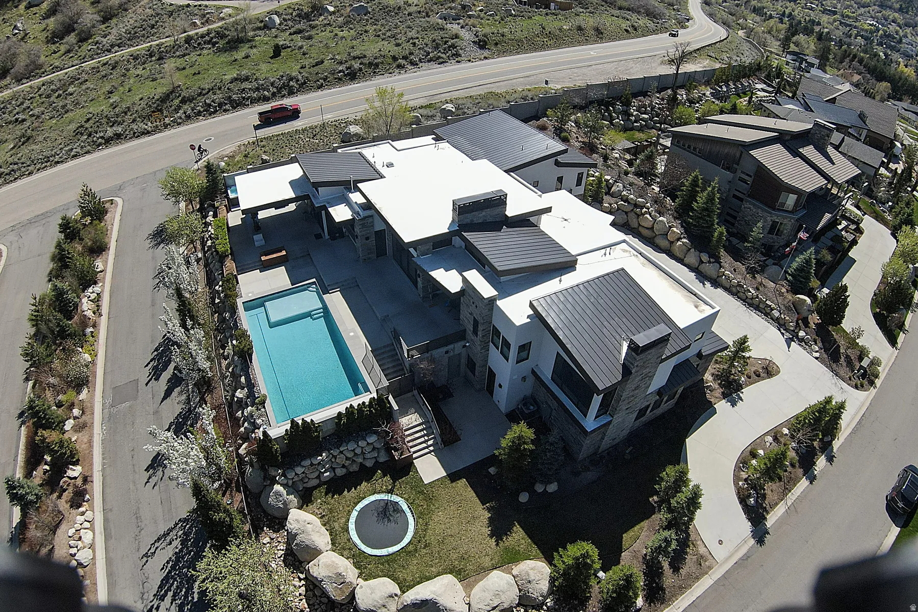 Contemporary residence featuring an integrated swimming pool, expansive paved patio, and multi-level landscaping