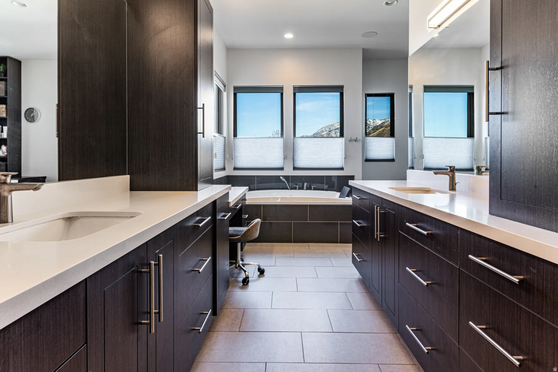 Master bathroom Dual wood-finish vanities with integrated sinks and light-toned countertops