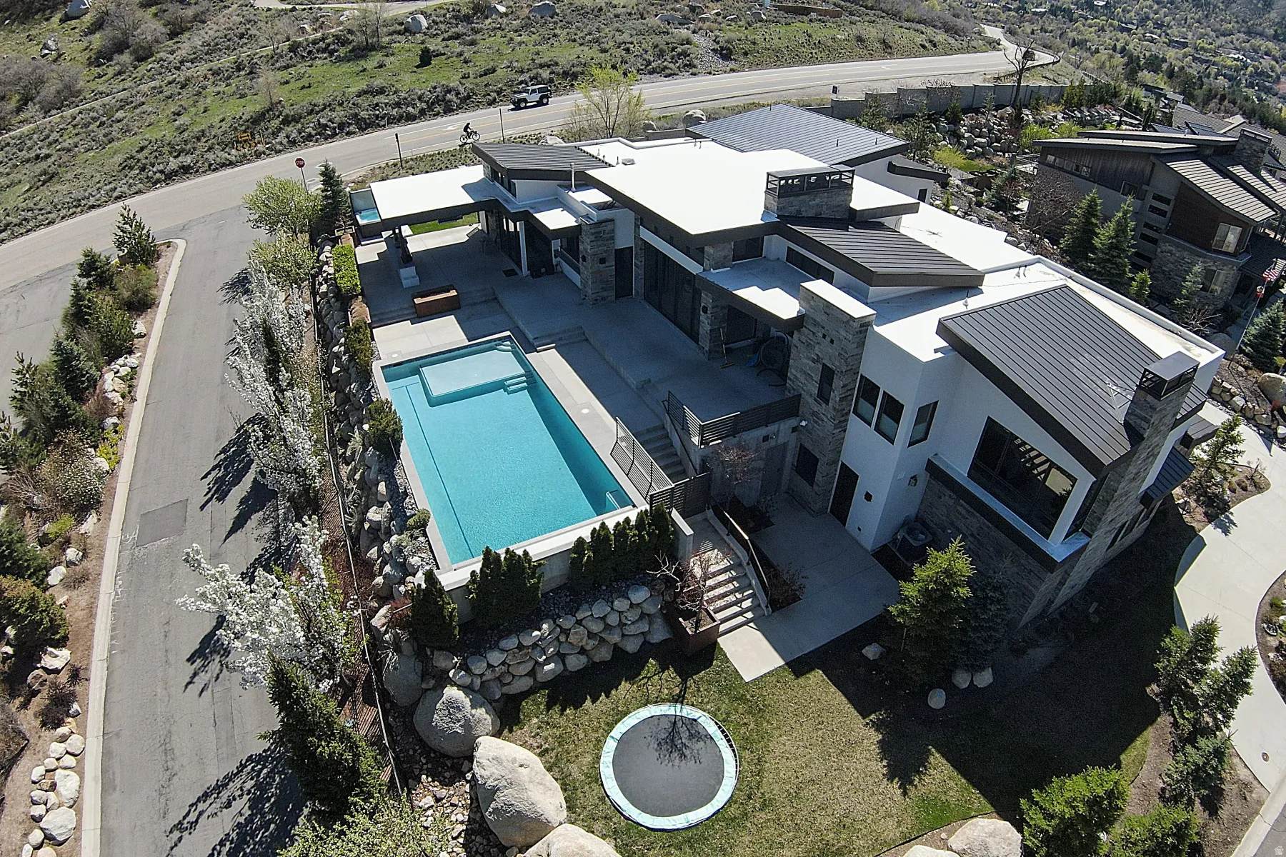 Contemporary residence featuring stone and stucco exterior finishes, a flat roofline, and an integrated swimming pool