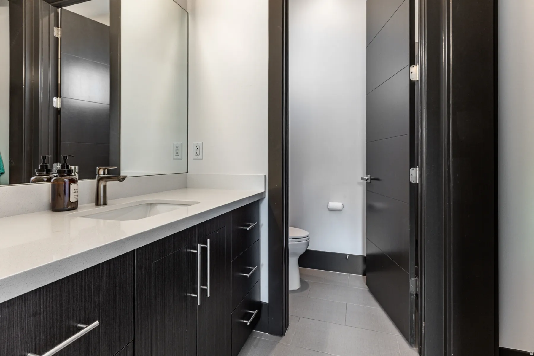 Bathroom 6 Vanity featuring a single undermount sink, a white countertop, and dark wood-finish cabinetry with silver-tone hardware