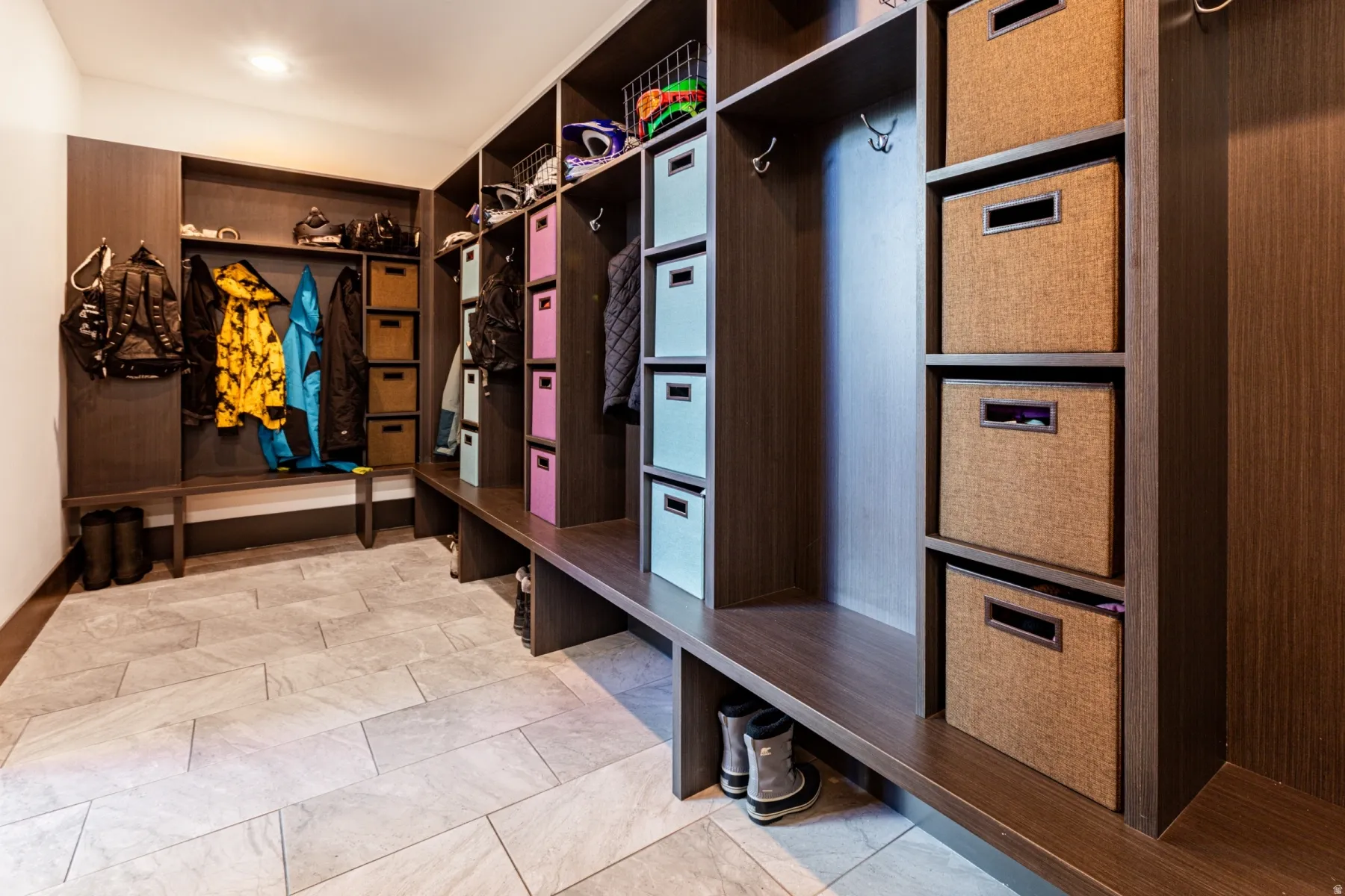 Custom-built storage system featuring a rich wood-finish, integrated bench seating, recessed lighting, and durable tile flooring