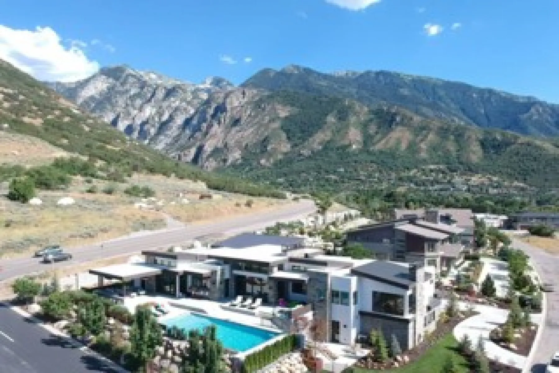 Modern architectural design featuring a rectangular swimming pool, integrated landscaping, stone accents, and a mountain backdrop