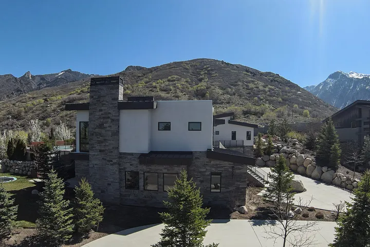 Modern architectural residence featuring a stone-clad chimney and a contrasting white facade