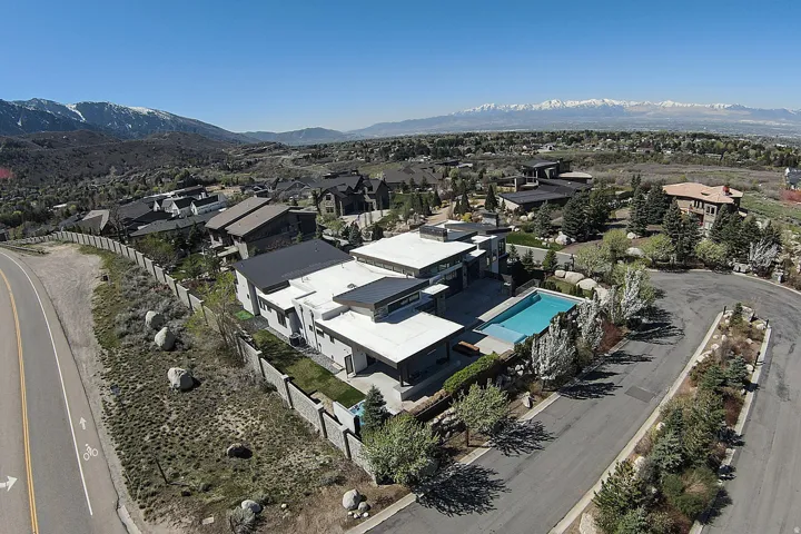 Modern architectural residence featuring a flat roofline, an exterior pool, a substantial privacy wall, and mature landscaping