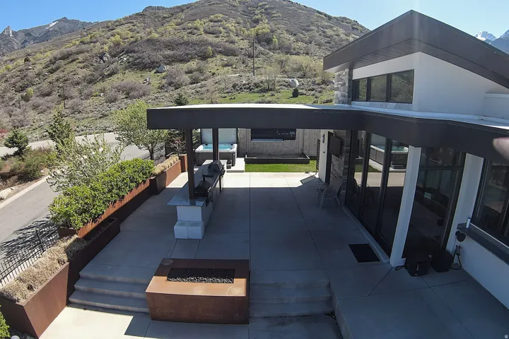 Expansive outdoor patio featuring a built-in grill station, fire pit, and a hot tub area