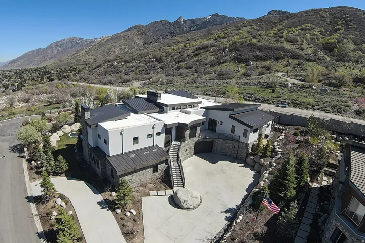 Contemporary architectural design featuring a multi-level structure with a mix of light-colored stucco and dark stone siding