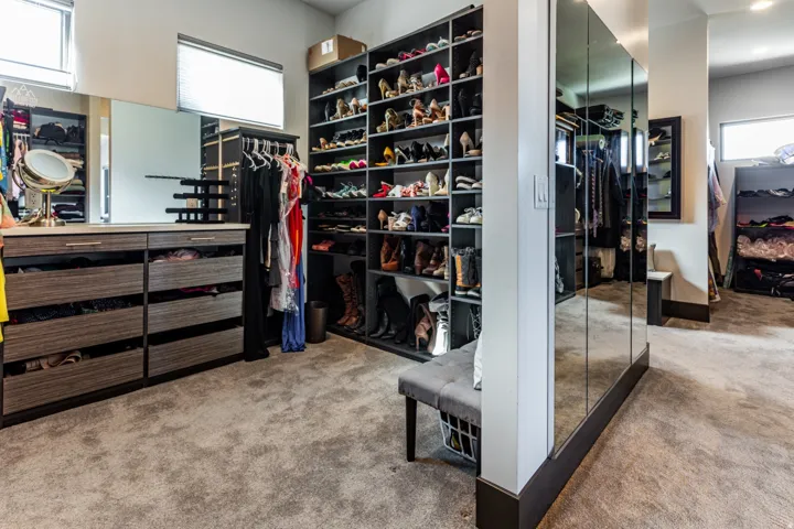Custom built-in closet system featuring extensive shelving, integrated drawers, full-length mirrored panels, and a central island with countertop space