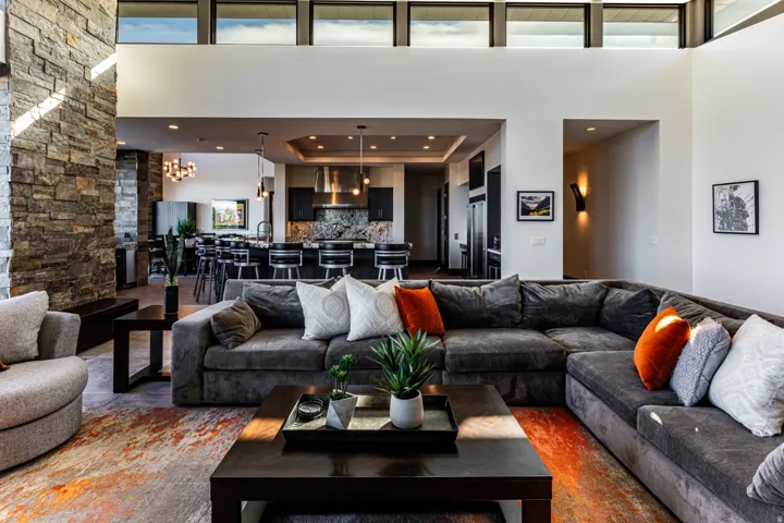 Expansive open-concept living area featuring a stone accent wall, high ceilings with transom windows, and recessed lighting