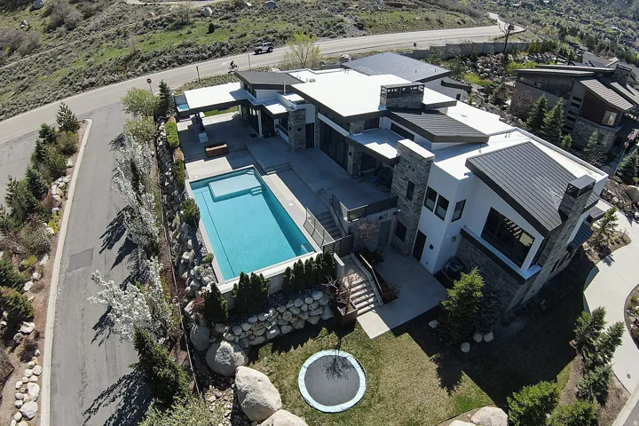 Contemporary residence featuring stone and stucco exterior finishes, a flat roofline, and an integrated swimming pool
