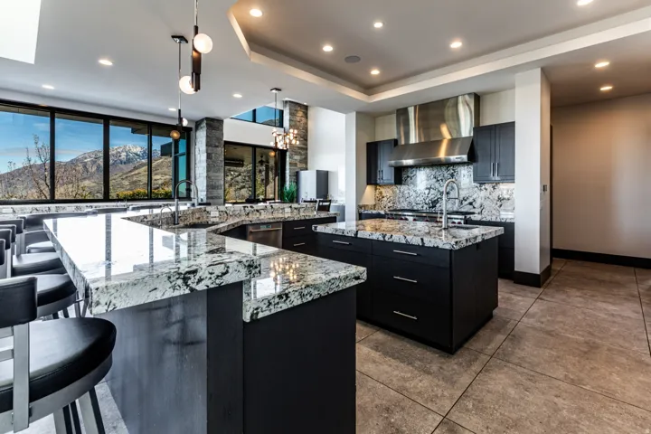 Modern kitchen featuring expansive counter space, a central island, dark cabinetry, stainless steel appliances, and large windows with mountain scenery