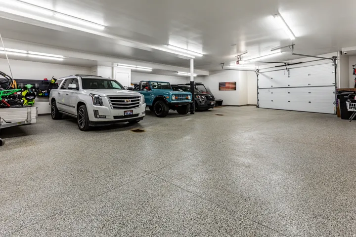 Spacious garage featuring a durable epoxy floor, overhead fluorescent lighting, and a white paneled garage door