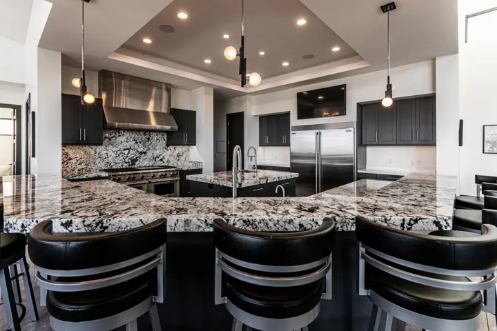 Gourmet kitchen featuring a large island with seating, a professional-grade range with a stainless steel hood, custom dark cabinetry, and integrated stainless steel appliances