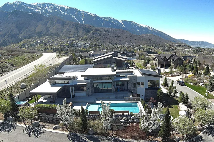 Contemporary architectural residence featuring a rectangular swimming pool, integrated spa, and an expansive paved patio