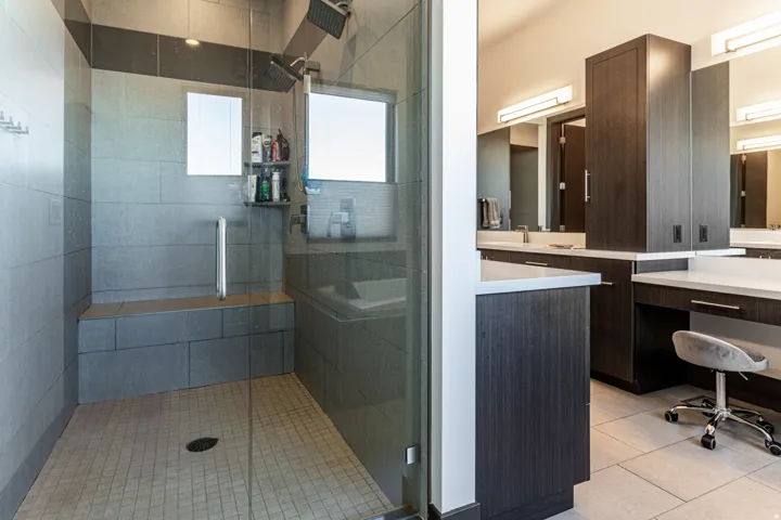 Glass-enclosed shower with a built-in bench, dual shower heads, and an integrated shelf
