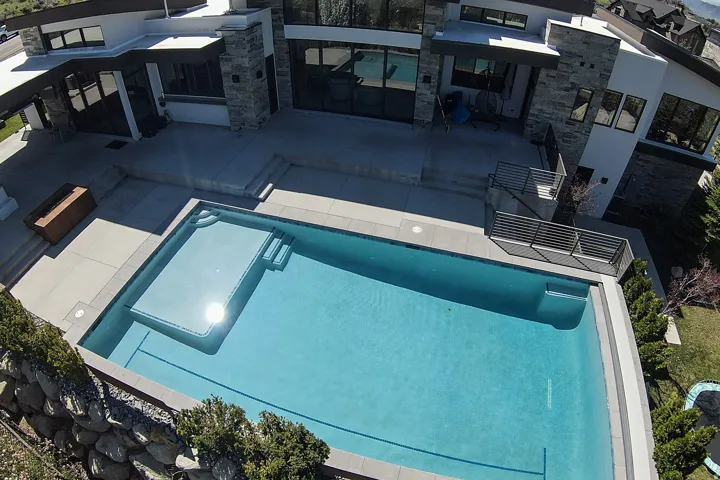 Contemporary exterior featuring multiple windows, a multi-level patio, and a rectangular swimming pool with an integrated sun ledge