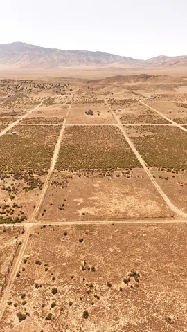 Expansive desert terrain featuring distinct land parcels and distant mountain ranges