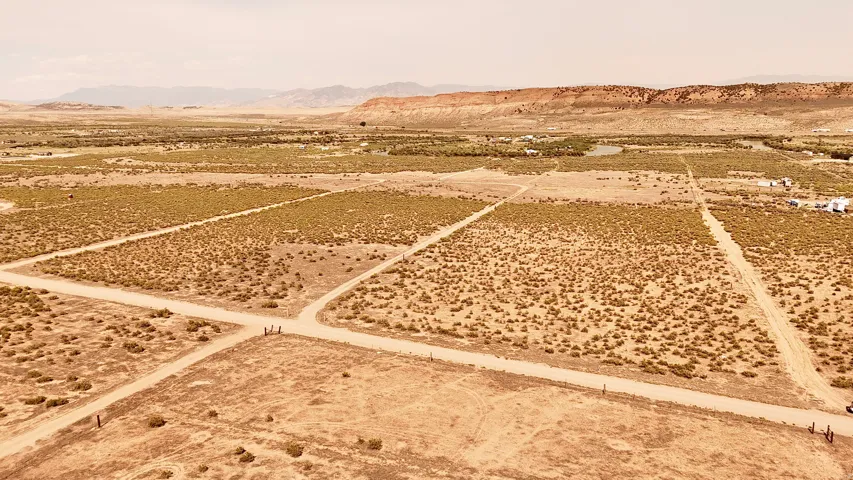 Expansive open land featuring a network of unpaved roads, natural vegetation, and distant mountain formations