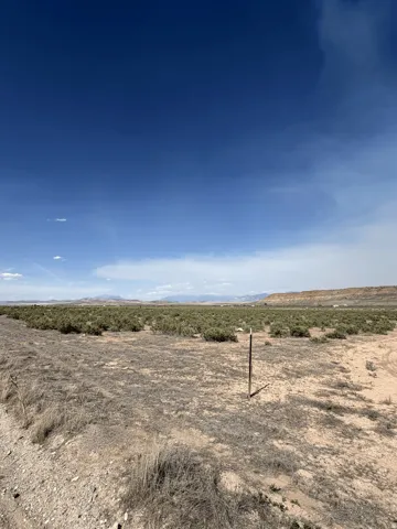Expansive undeveloped land featuring natural desert vegetation, a clear blue sky, and distant mountain ranges