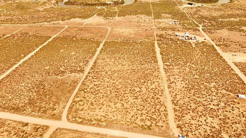 Expansive undeveloped land featuring natural desert vegetation, multiple cleared pathways, and a winding waterway bordering the property