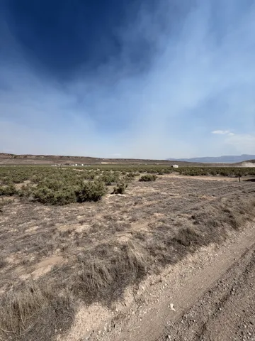 Expansive open terrain featuring natural vegetation and distant hills under a vast sky