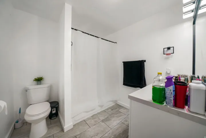 Bathroom featuring a white shower curtain, vanity with a light-colored countertop, wall-mounted mirror, and tile flooring