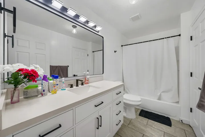 Bathroom featuring a white vanity with integrated sink, dark bronze hardware, and a matching mirror and light fixture