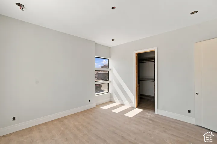 Recessed ceiling lighting, multiple windows, wood-finish flooring, built-in closet, and a neutral color palette