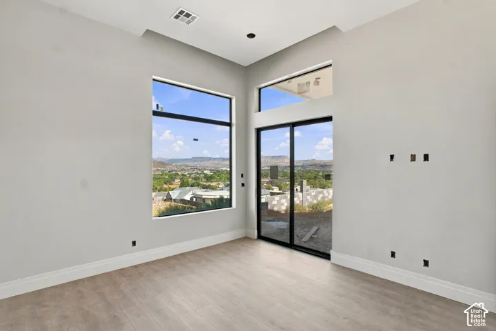 Vaulted ceiling, floor-to-ceiling windows, sliding glass door, wood-finish flooring, recessed lighting