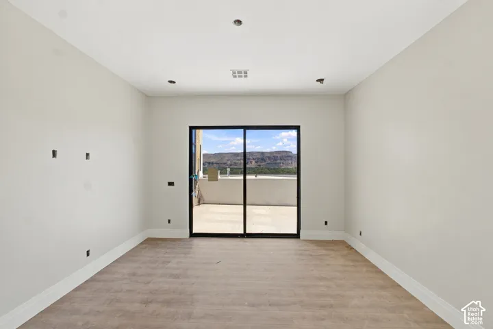 Sliding glass door with black framing, wood-finish flooring, recessed lighting, and bright white walls