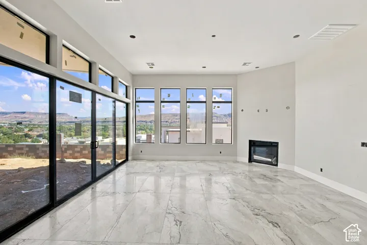 Expansive window wall with multiple panes and a glass door, contemporary fireplace, recessed lighting, and large format tile flooring