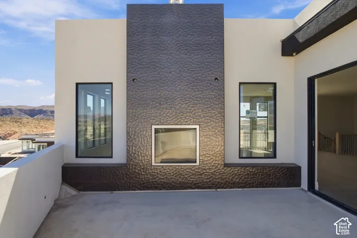 Outdoor living space featuring a textured fireplace wall, built-in hearth, and expansive sliding glass doors