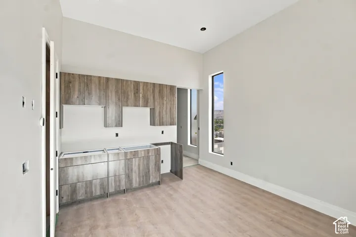 Wood-finish flooring with built-in cabinetry, upper and lower storage, and a tall, narrow window
