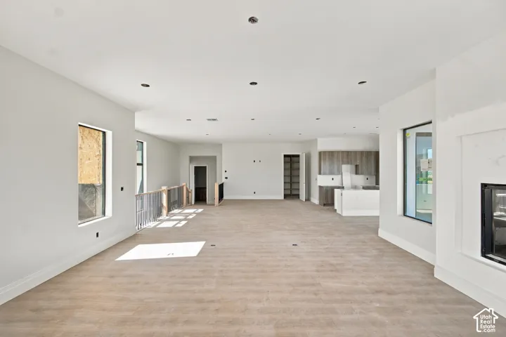 Expansive open-concept space featuring wood-finish flooring, a built-in fireplace, and a kitchen area with cabinetry