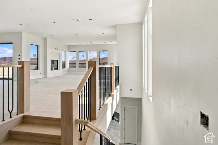 Wood-finish flooring, staircase with wood newel posts, black metal balusters, integrated fireplace, and multiple windows