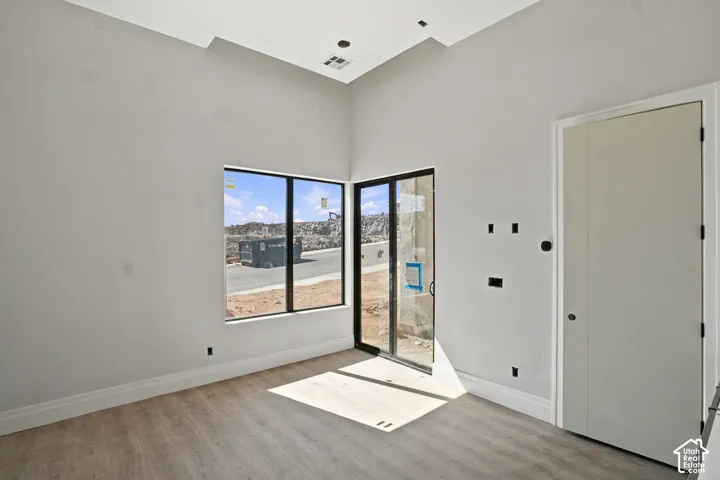 Vaulted ceiling with recessed lighting, large pane windows, glass sliding door, and wood-finish flooring