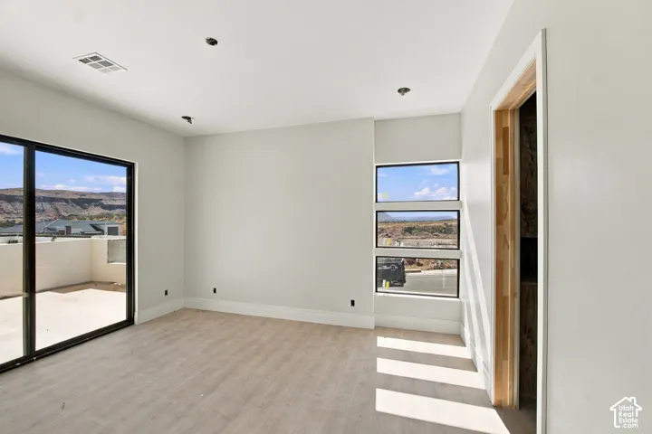 Wood-finish flooring, recessed ceiling lighting, a sliding glass door to an outdoor patio, and three rectangular windows