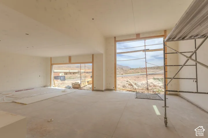Expansive interior space featuring large window openings, unfinished walls, and a concrete floor