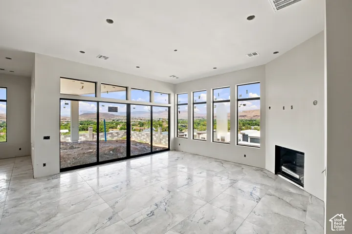 Expansive room featuring large format tile flooring, recessed lighting, a built-in fireplace, and floor-to-ceiling windows with transoms
