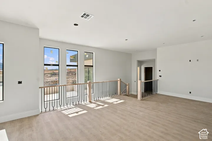 Expansive open-concept room featuring multiple tall windows and wood-finish flooring
